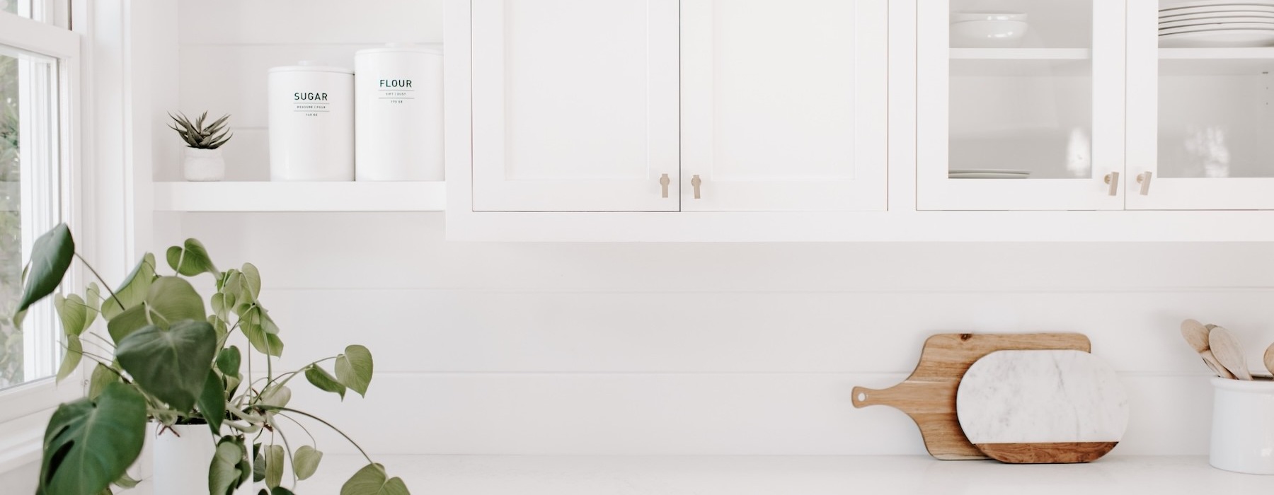 a counter with decorations and a plant with white cabinets above it